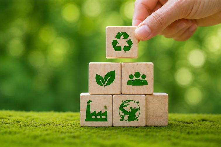 image illustrant des critères environnementaux et sociaux avec des cubes en bois portant des symboles écologiques et une main plaçant un bloc recyclage.